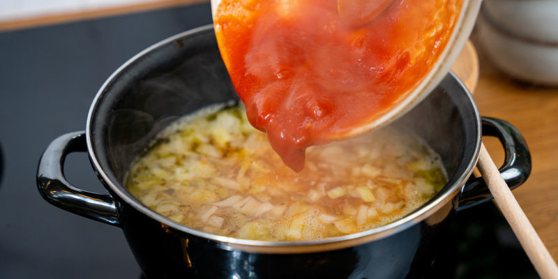 Junte os tomates ou o puré de tomate e o caldo de legumes; reduza o lume e deixe ferver suavemente